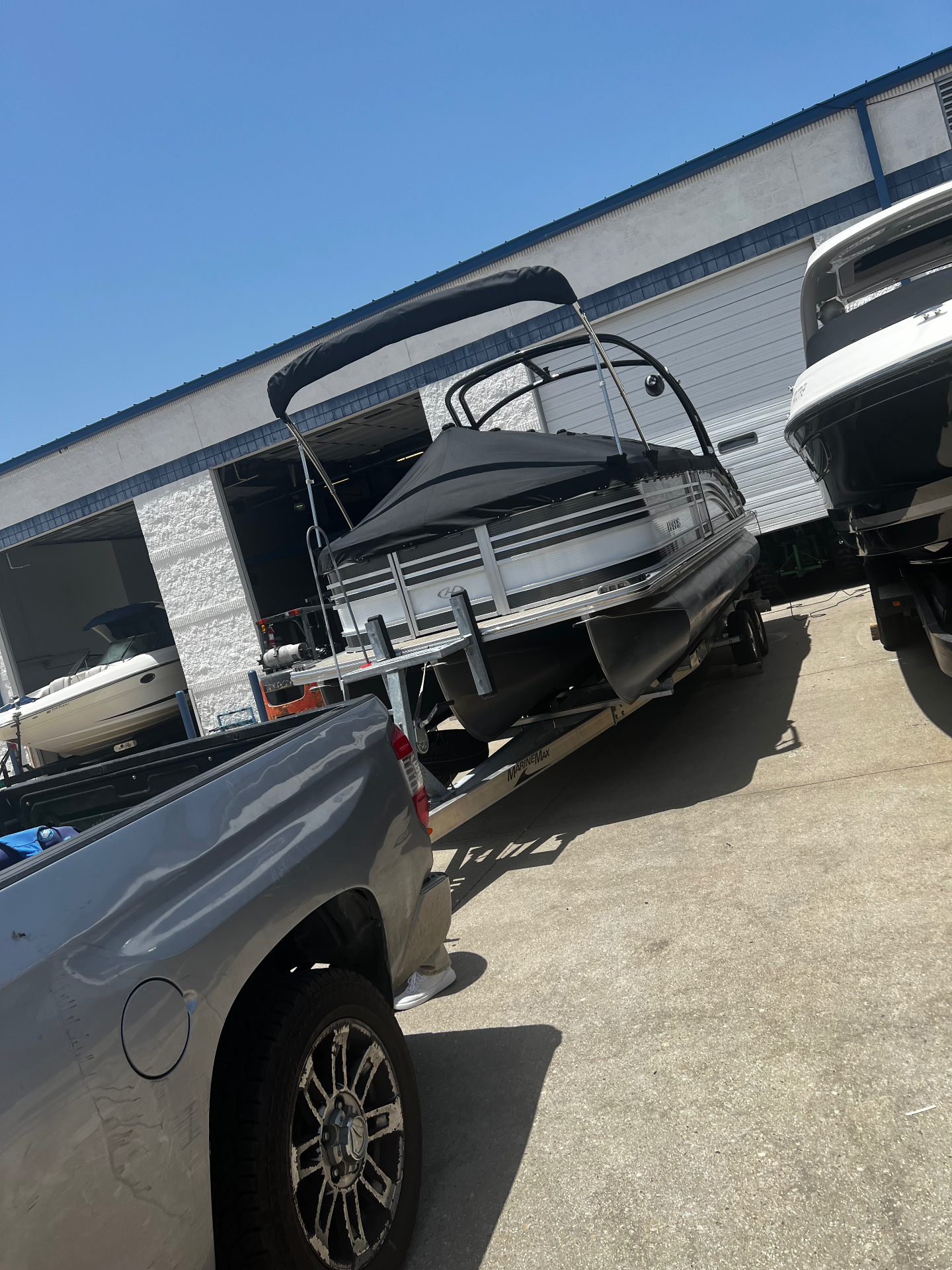 Pontoon boat loaded on a trailer behind a truck at a boat storage facility